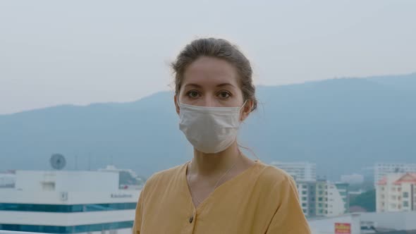 Portrait of a Beautiful Young Woman Wearing Protective Medical Face Mask and Standing on the Rooftop