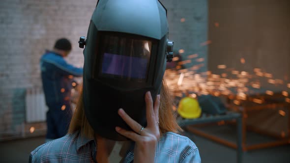 Young Sexy Smiling Woman Standing in the Workshop Taking Off Her Protective Mask