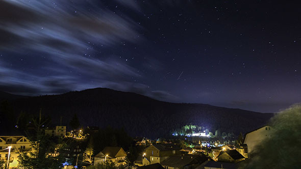 Stars Moving in Night Sky Over Mountain City