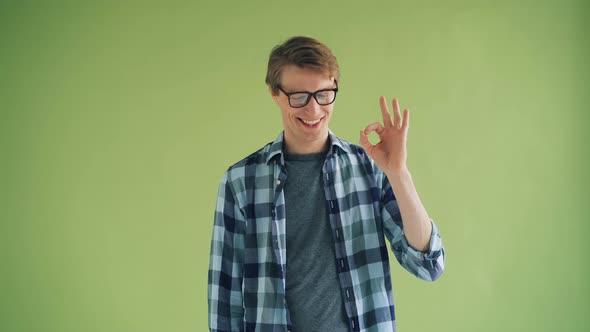 Portrait of Cheerful Young Man Showing OK Gesture and Smiling Looking at Camera