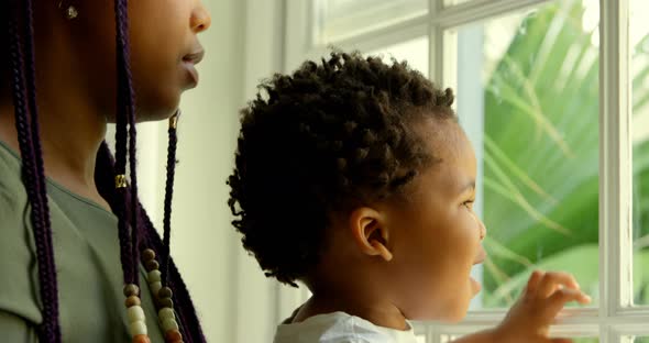 Close-up of young black mother playing with his son on window sill in a comfortable home 4k