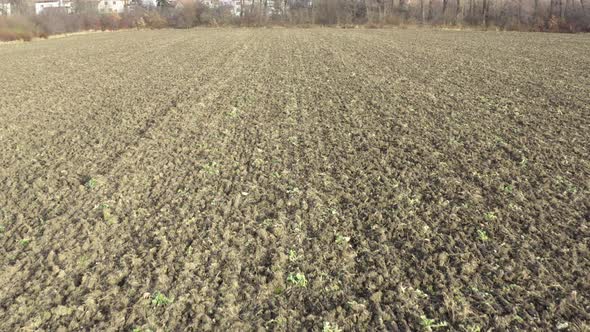 Aerial Shot of Plowed Empty Field During Winter on Day - Buildings in the Background - Slow Move