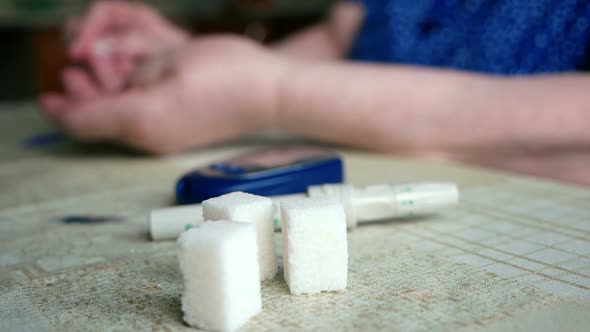 A woman with diabetes at home sitting at the table makes a sugar test using a glucometer
