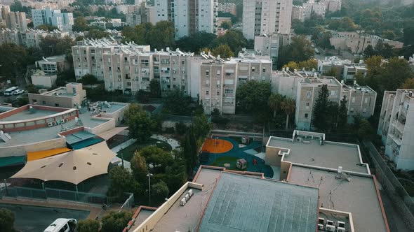 Aerial Tracking Past Sunlit Houses on Hilltop at Sunrise in Haifa Israel