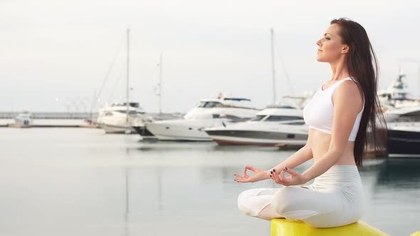 Beautiful Girl with Long Brown Hair in Sport Clothes Relaxing on Sea Dock After Early Workout