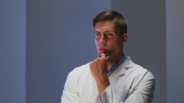 Handsome caucasian male doctor wearing lab coat looking at information using virtual digital interfa