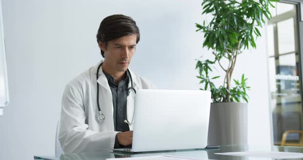 Young male doctor working on laptop 4k