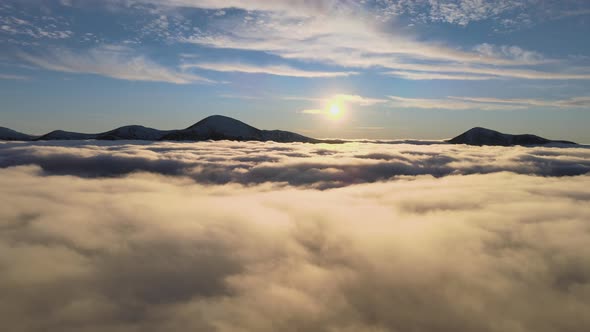 Aerial View of Vibrant Sunrise Over White Dense Fog with Distant Dark Peaks of Carpathian Mountains