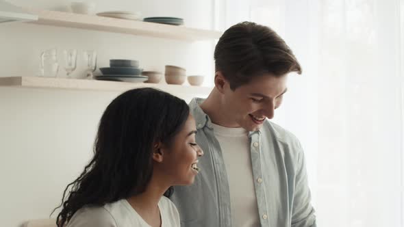 Diverse Couple Feeding Each Other Cooking Preparing Dinner In Kitchen