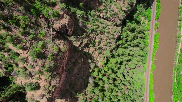 Aerial Footage Hovering Over Steep Gorge Canyon Cliffside Covered In Bright Healthy Green Trees Near