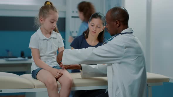 Male Doctor Applying Bandaid on Child with Injured Arm