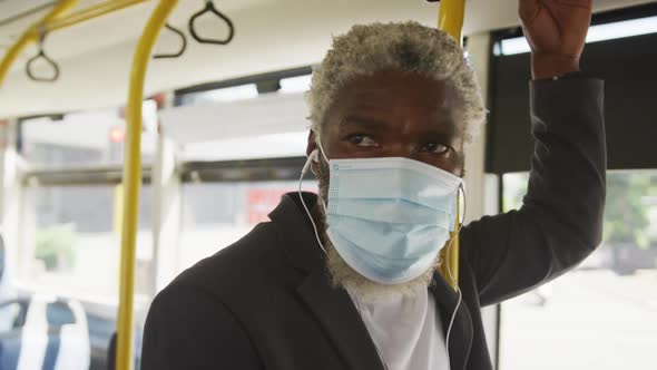 African american senior man wearing face mask travelling in the bus