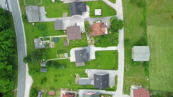 Flying between green meadows and over small settlement of medium size family houses