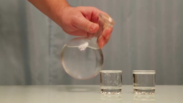 Hand Pouring Vodka Into Glasses From Carafe