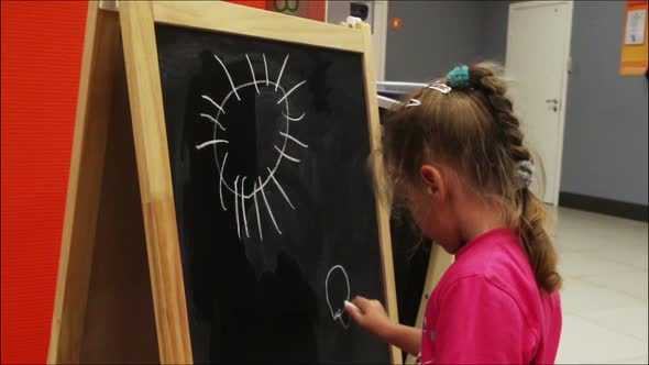 Little Girl Drawing Sun  Chalk On Blackboard 2