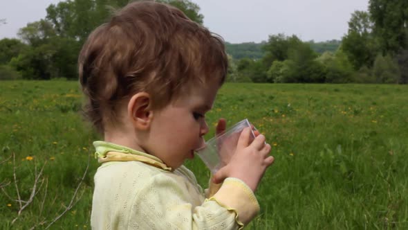 Child Eats Cucumber On Summer Lawn alt