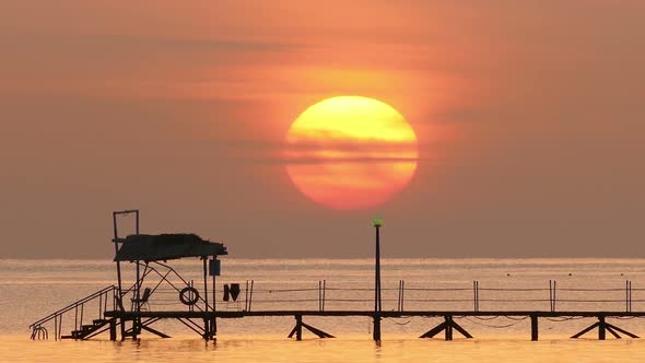 Beautiful Sunrise Over Pier In Sea - Filmed At Telephoto Lens, Zoom Out