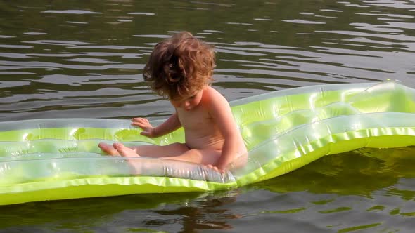 Baby Bathing In River On Inflatable Mattress 1