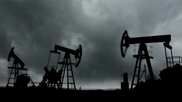 Working Oil Pumps Silhouette Against The Background Of The Darkest Storm Clouds