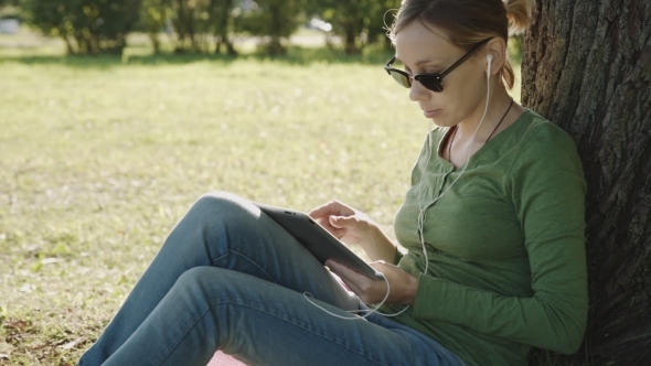 Girl In The Park And Use Tablet Pc
