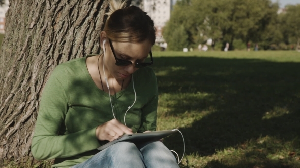 Girl In The Park And Use Tablet Pc