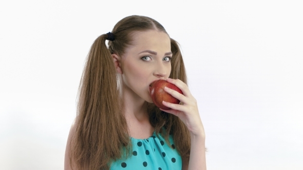 A Young Girl With Tails On Head Eating Red Apple