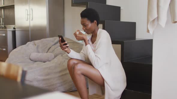 Happy african american woman sitting on stairs talking on smartphone