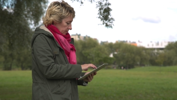 Adult Woman Using Tablet Pc In The Park