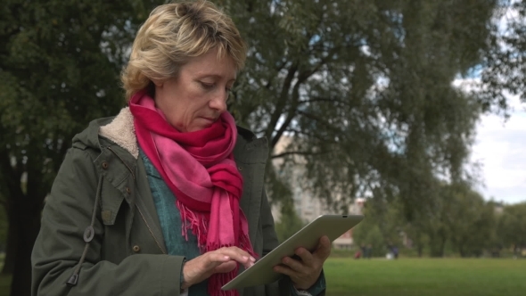 Adult Woman Using Tablet Pc In The Park