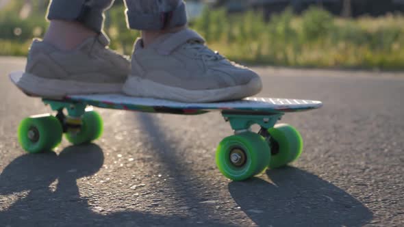 Close Up Legs Riding on Skateboard in Motion of Asphalt at Sunset. Youth Leisure Concept. Active