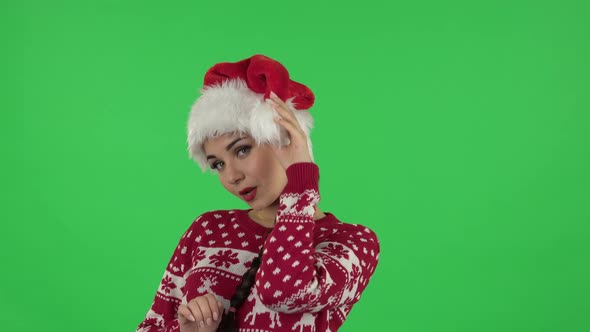 Portrait of Sweety Girl in Santa Claus Hat Is Coquettishly Smiling While Looking at Camera. Green