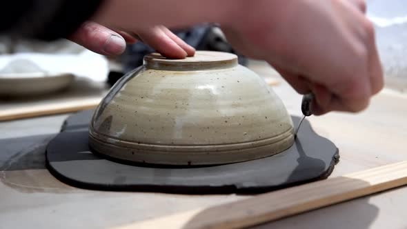 Clay being trimmed in a circle with knife using a bowl as guide by hand on a ceramics workshop, Hand