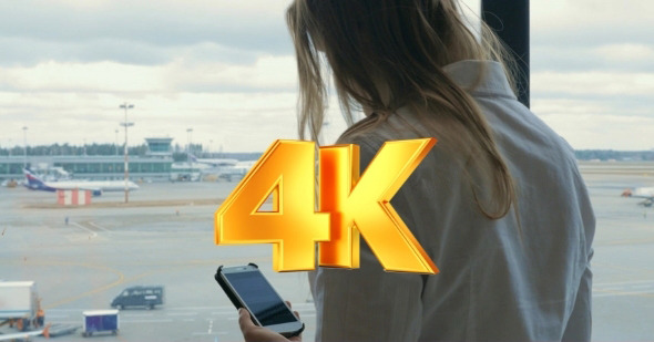 Woman Texting On Cell And Looking At Airport Area alt