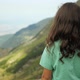 Cinematic back view of a girl looking out over a green valley of mountains. - VideoHive Item for Sale
