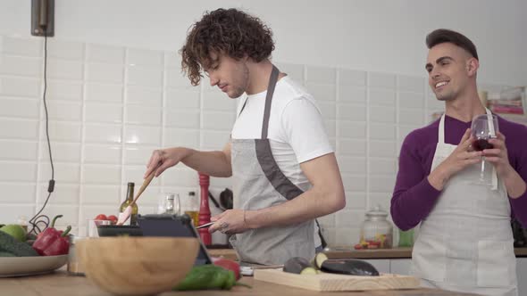 Young Male Gay Couple Cooking Together at Home and Lovely Embracing Each Other in the Kitchen