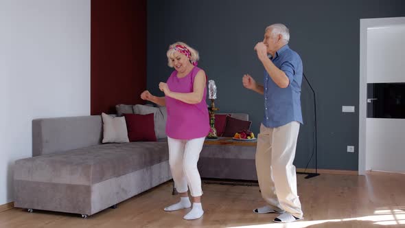 Senior Couple Dancing Laughing at Home. Grandparents Relaxing Having Fun Celebrating Anniversary
