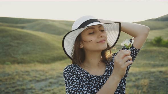 Woman With Hat Smelling A Flower
