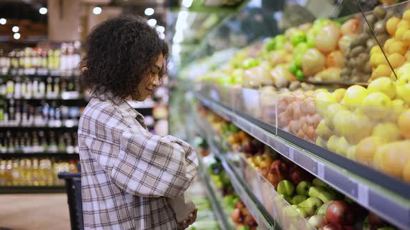 Smiling Woman Choosing Fresh Fruits in Supermarket Into Paper Bag