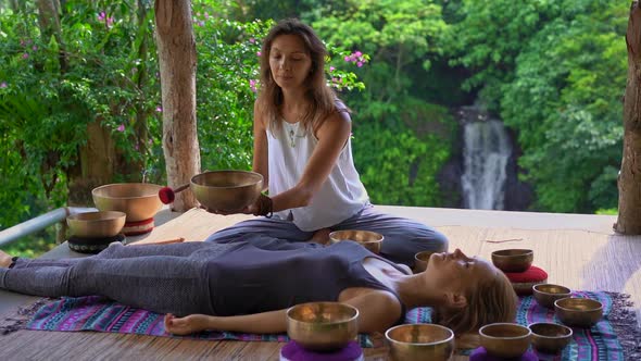 Superslowmotion Shot of a Woman Master of Asian Sacred Medicine Performs Tibetan Bowls Healing