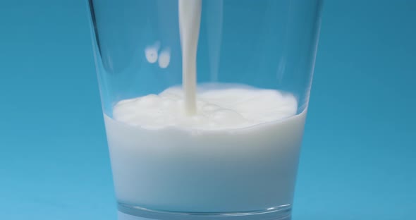 Milk is poured into a milk glass on a blue background.