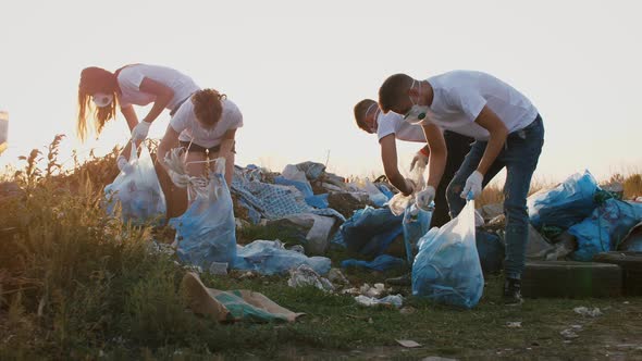 Group of Eco Volunteers Cleaning Up Area of Dump Near the Field During Sunset