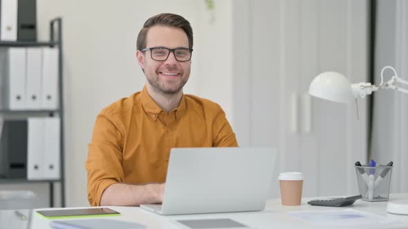 Young Man with Laptop Smiling at the Camera 