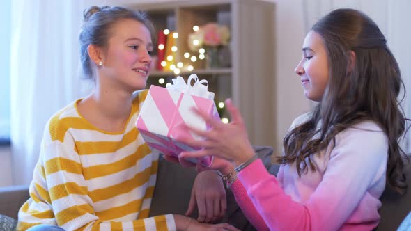 Teenage Girl Giving Present To Her Friend at Home