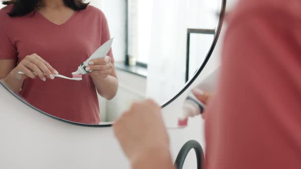 Close-up of Woman's Hand Squeezing Toothpaste on Brush in Bathroom Ready To Clean Her Teeth