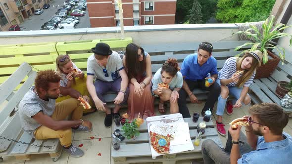 High angle view of friends eating pizza on the rooftop terrace