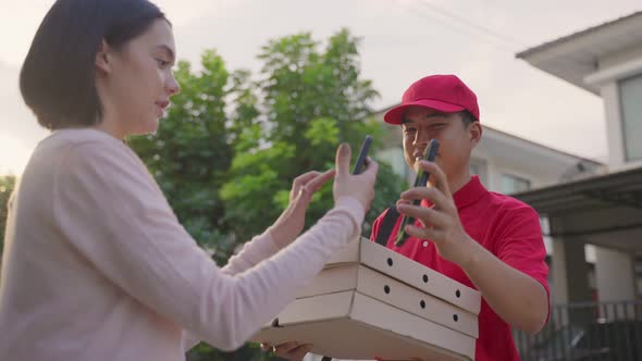 Asian deliver man worker in red color uniform handling bag of food, pizza give to customer girl.