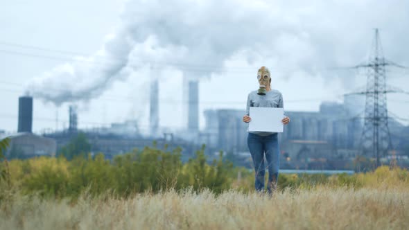 Girl in a Gas Mask on a Background of Smoky Pipes of a Factory