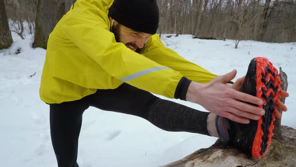 Bearded Athletic Fit Man Stretching Legs before Running in Winter Rorest