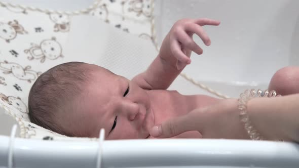 Happy newborn baby lies and smiles when he is bathed in the bathtub
