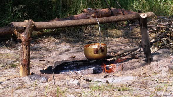 Cooking on an Open Fire in a Tourist Pot. Tourist Bowler Hat Hanging at Bonfire